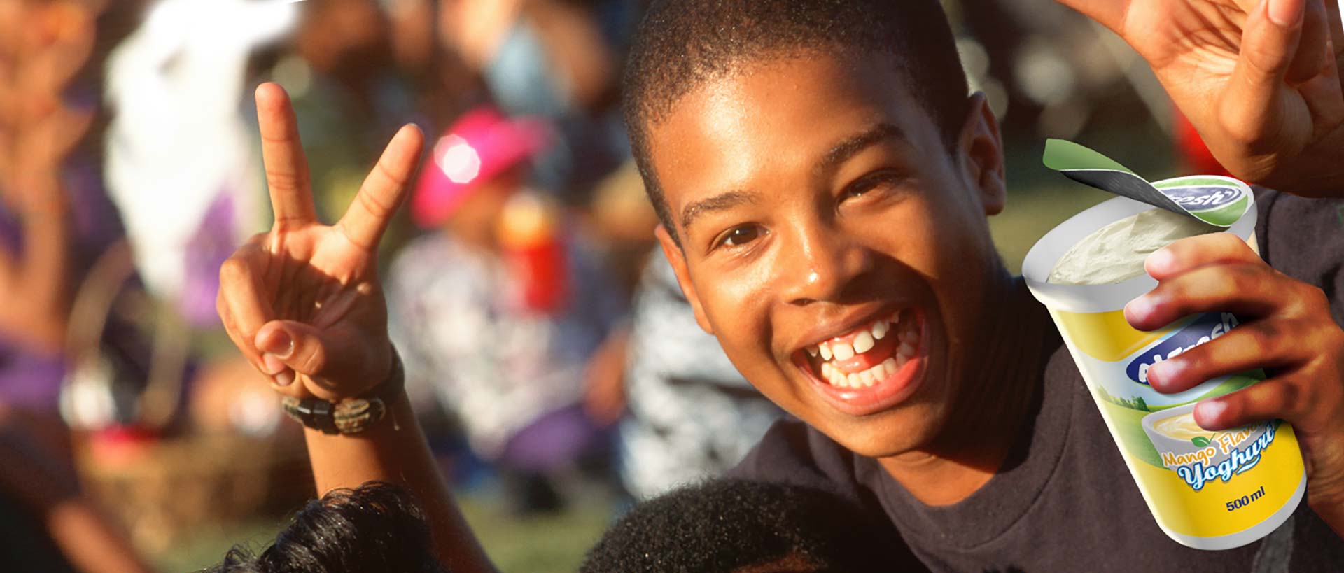 Canaan Factories Limited - Young boy smiling while holding a container of Alfresh yoghurt